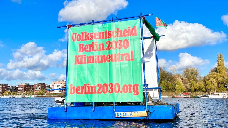 Transparent auf einem Floss im Wasser: „Volksentscheid Berlin 2030 Klimaneutral“